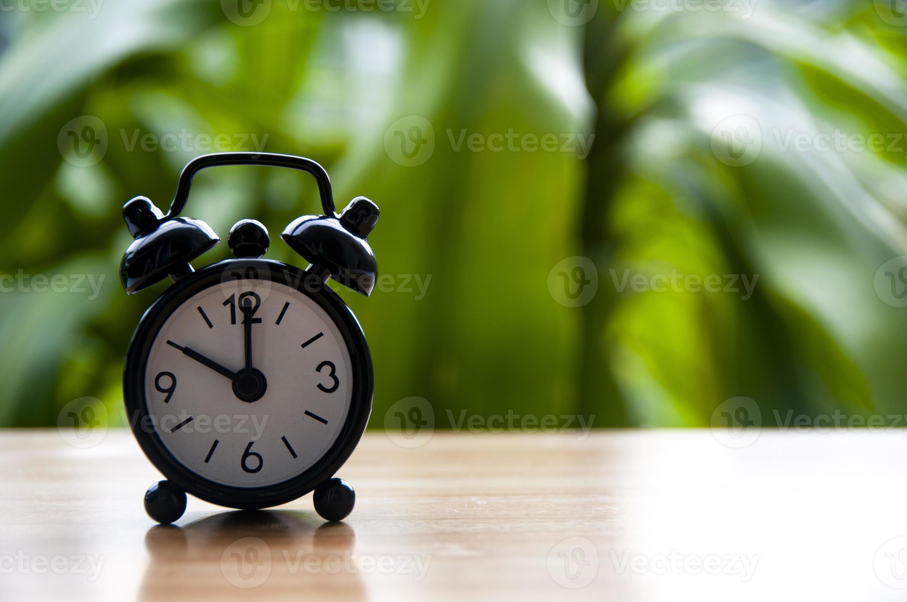 Alarm clock pointing at 10am with blurred nature background. With