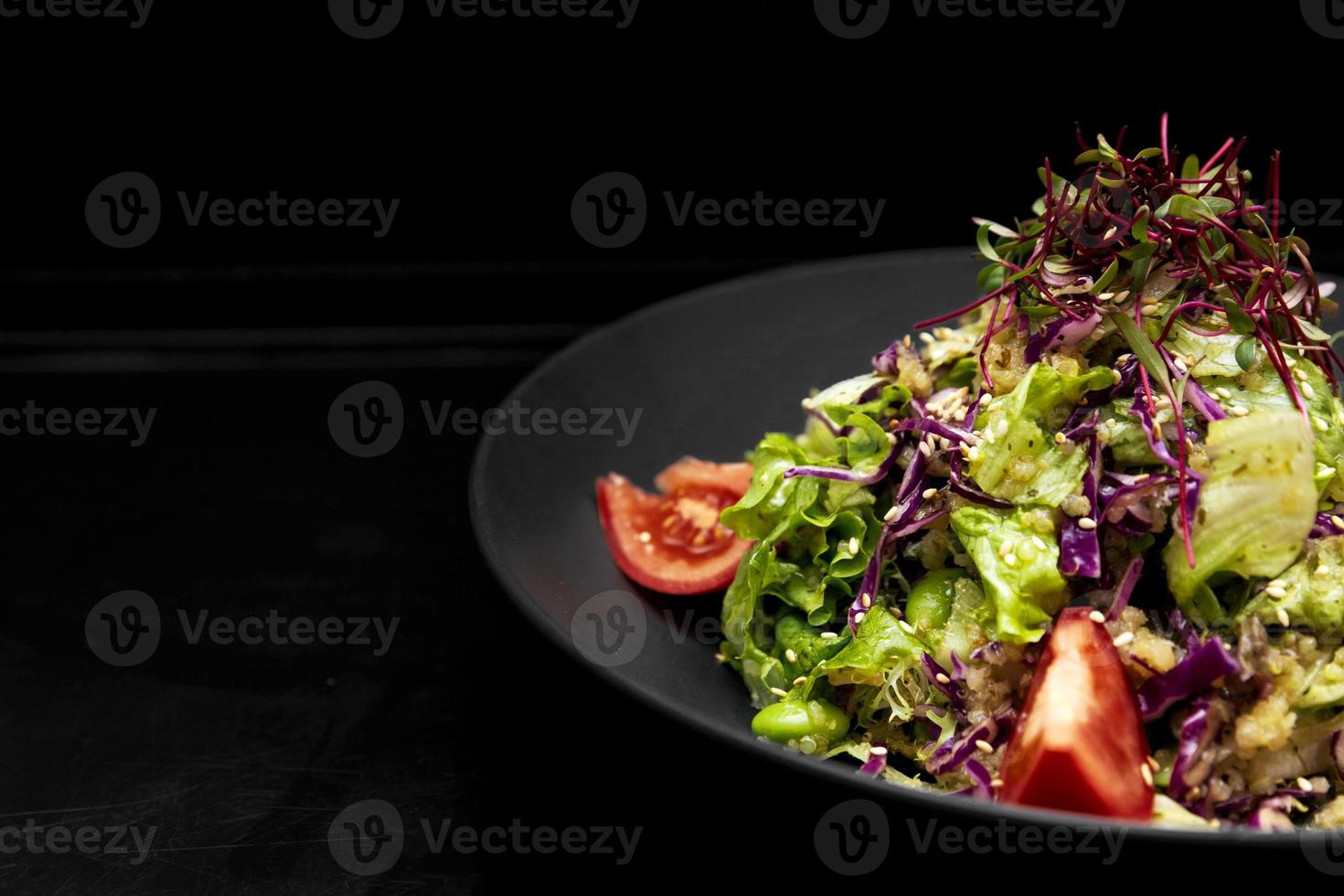 salad in a black plate, on a black wooden background photo