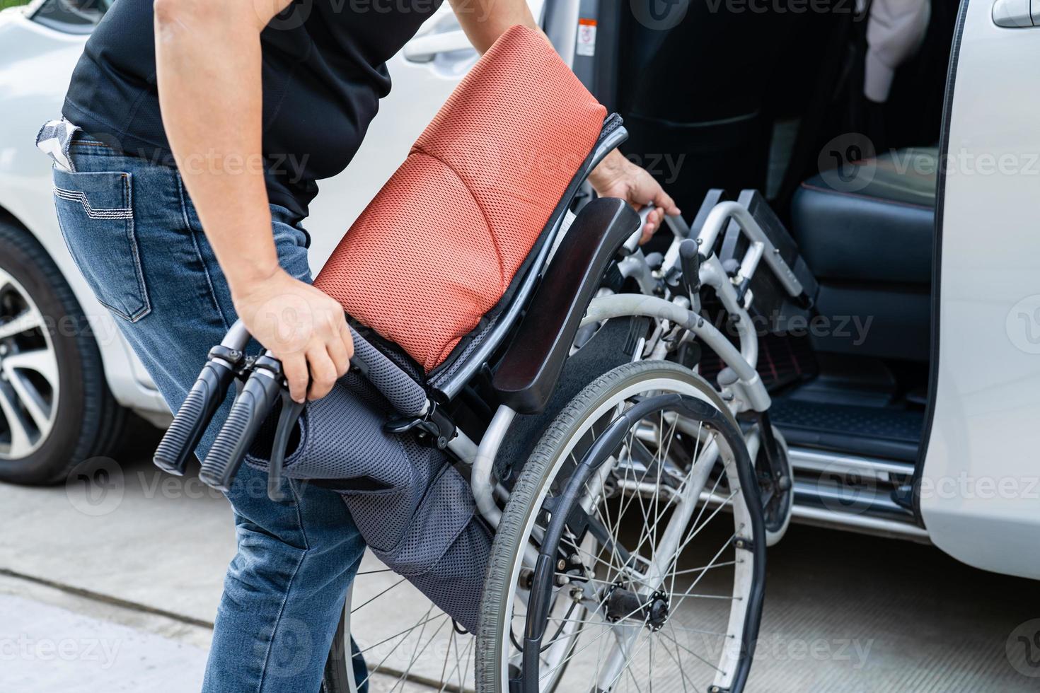 Asian woman folding and lift up wheelchair into her car. Accessibility concept. photo