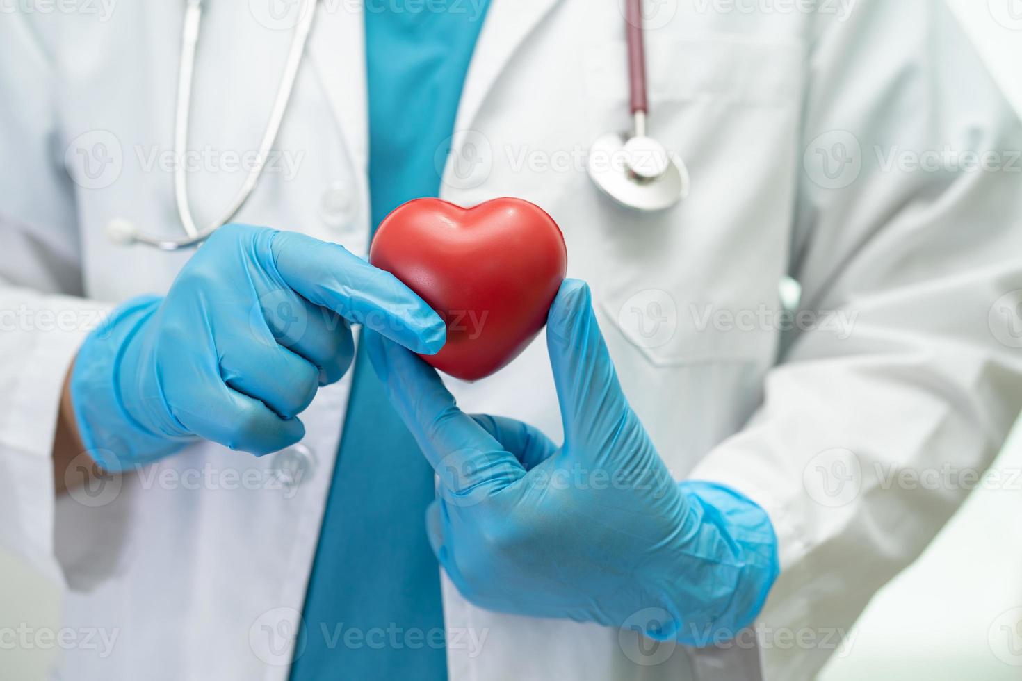 Doctor holding a red heart in hospital ward, healthy strong medical concept. photo