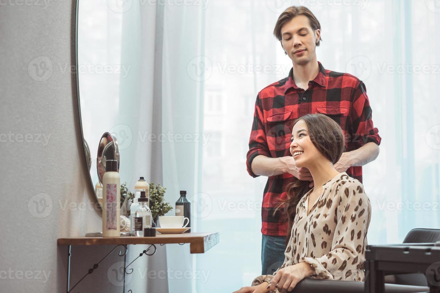 peluquero estilista peinando cabello largo para una hermosa joven asiática en el salón de belleza, momento de trabajo foto