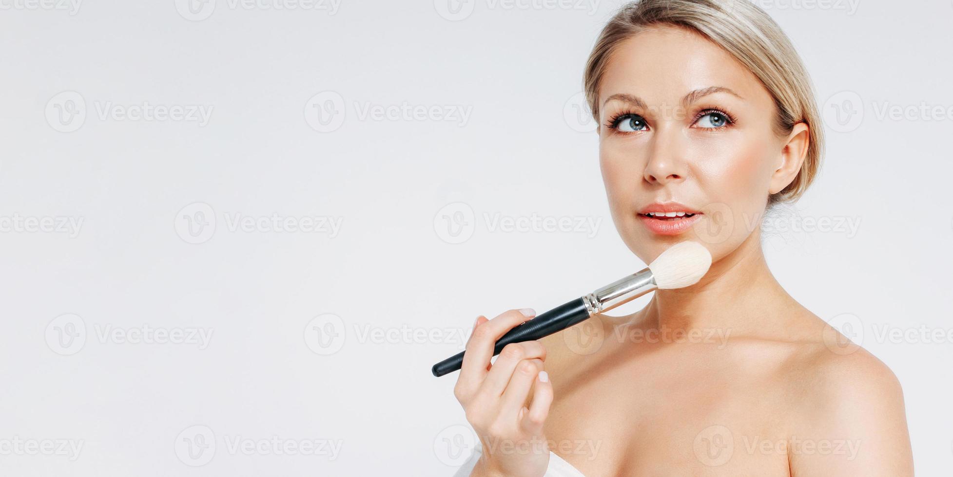 Beauty blonde smiling woman 35 year with brush near clean fresh face isolated on white background, banner photo