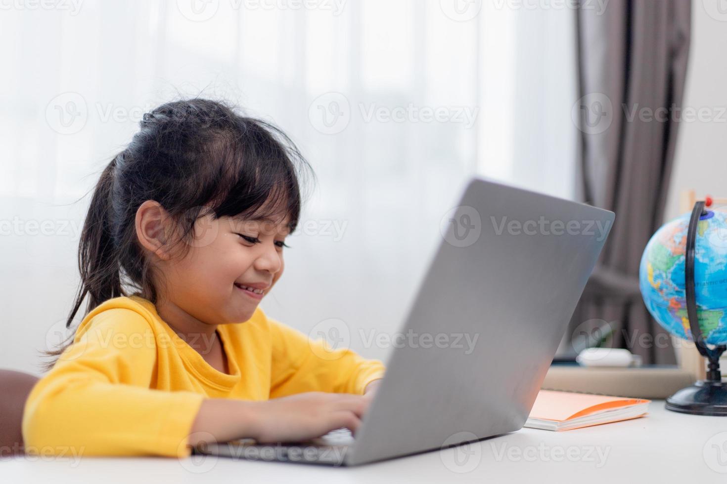 First day at school. Asian little girl using a laptop computer, studying through online e-learning system. photo