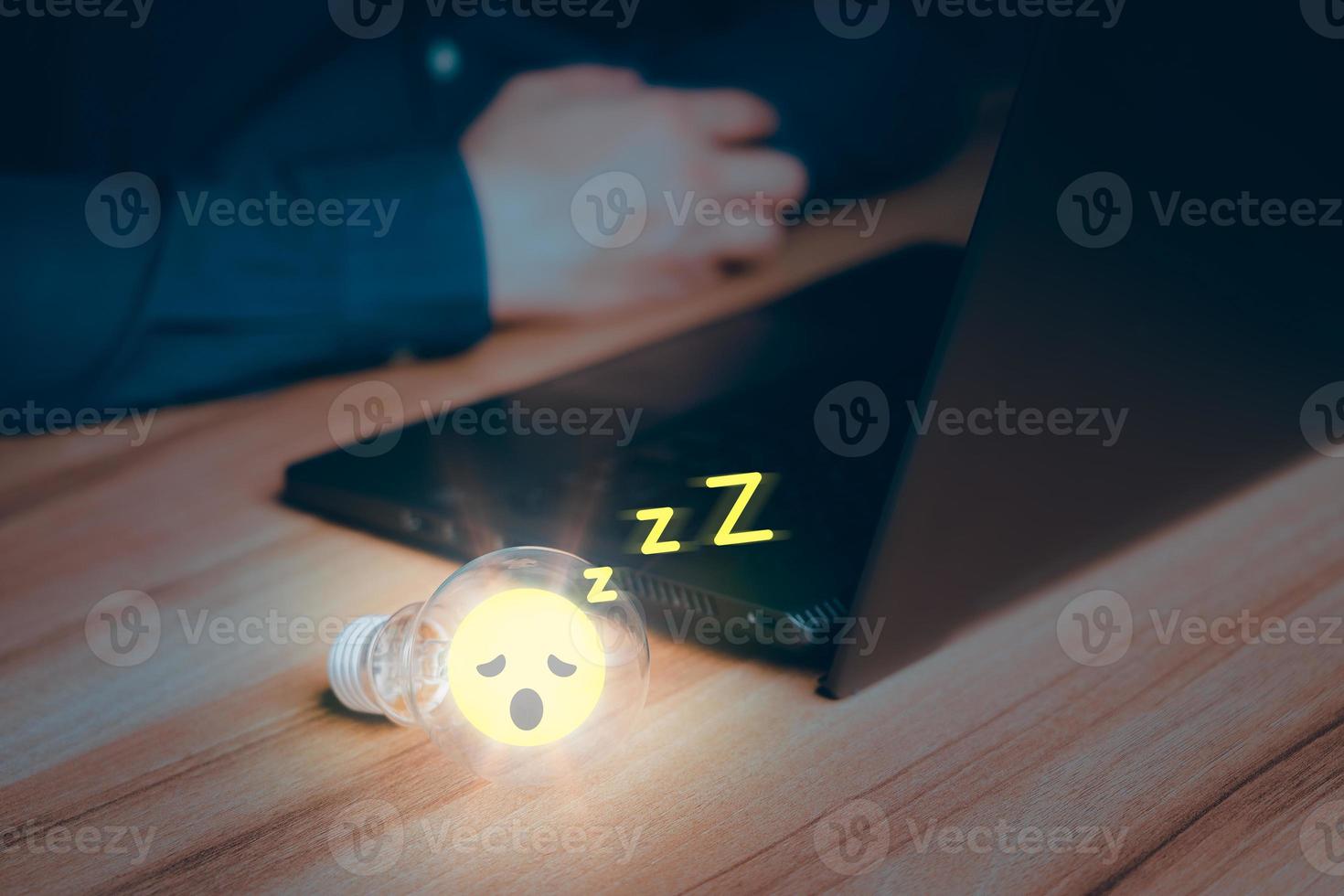 Man put a glowing a light bulb wiht sleepy icon on a wooden table, business problem solving ideas and creative marketing ideas Inventing and learning new things. photo
