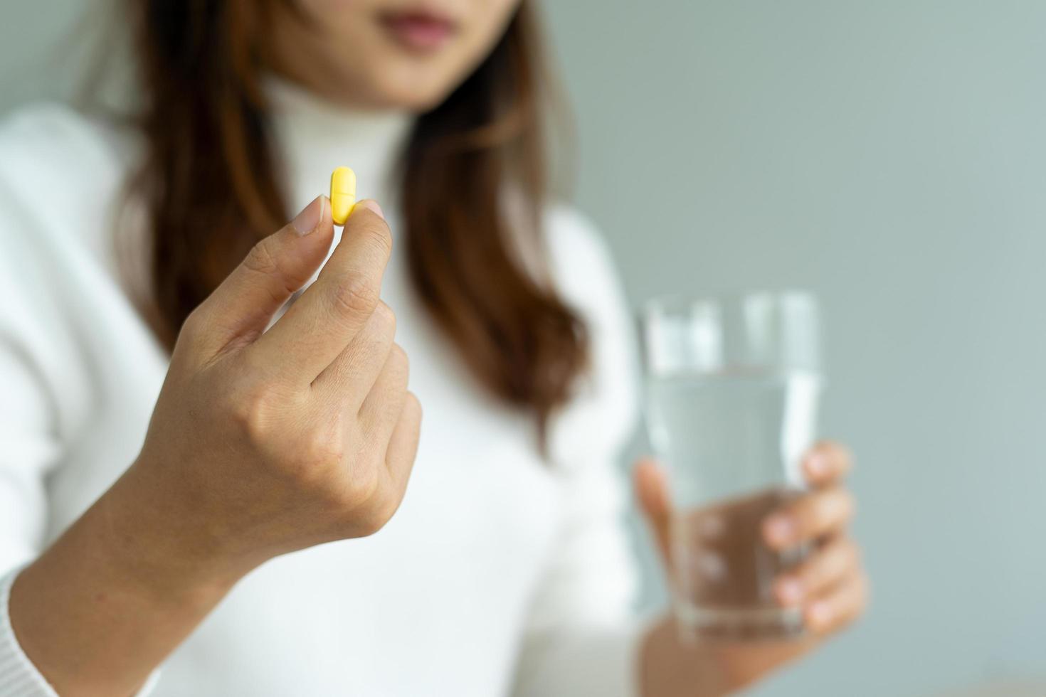 Close up of hand's woman holding a dietary supplement or medication or vitamin and a glass of water ready to take. healthcare, medicine,Self-care,Illness and pharmacy concept. photo