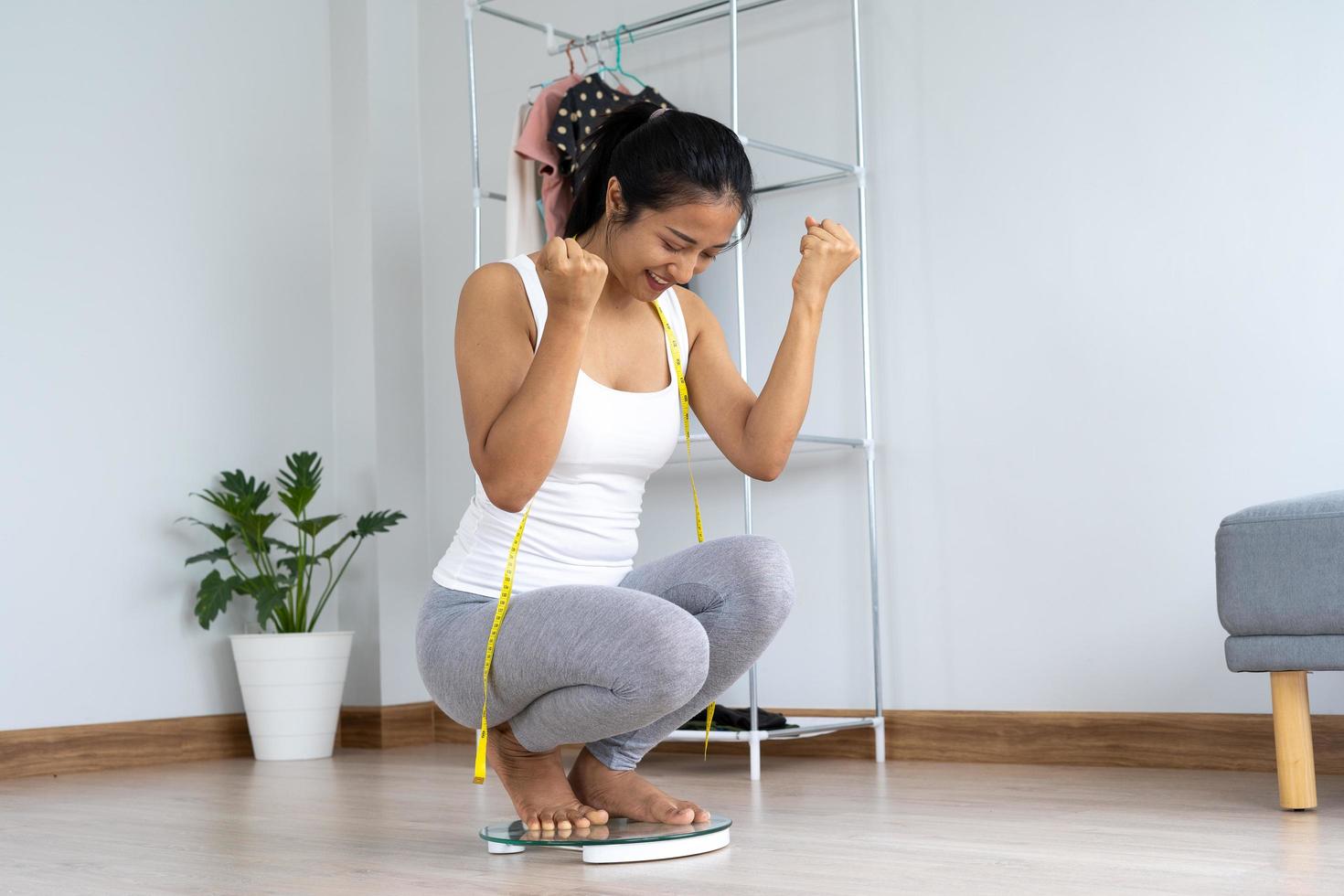 A happy Asian woman smiled on the scales at home. Women show ecstasy after weighing and receiving their intended results. Concept of diet, health care photo