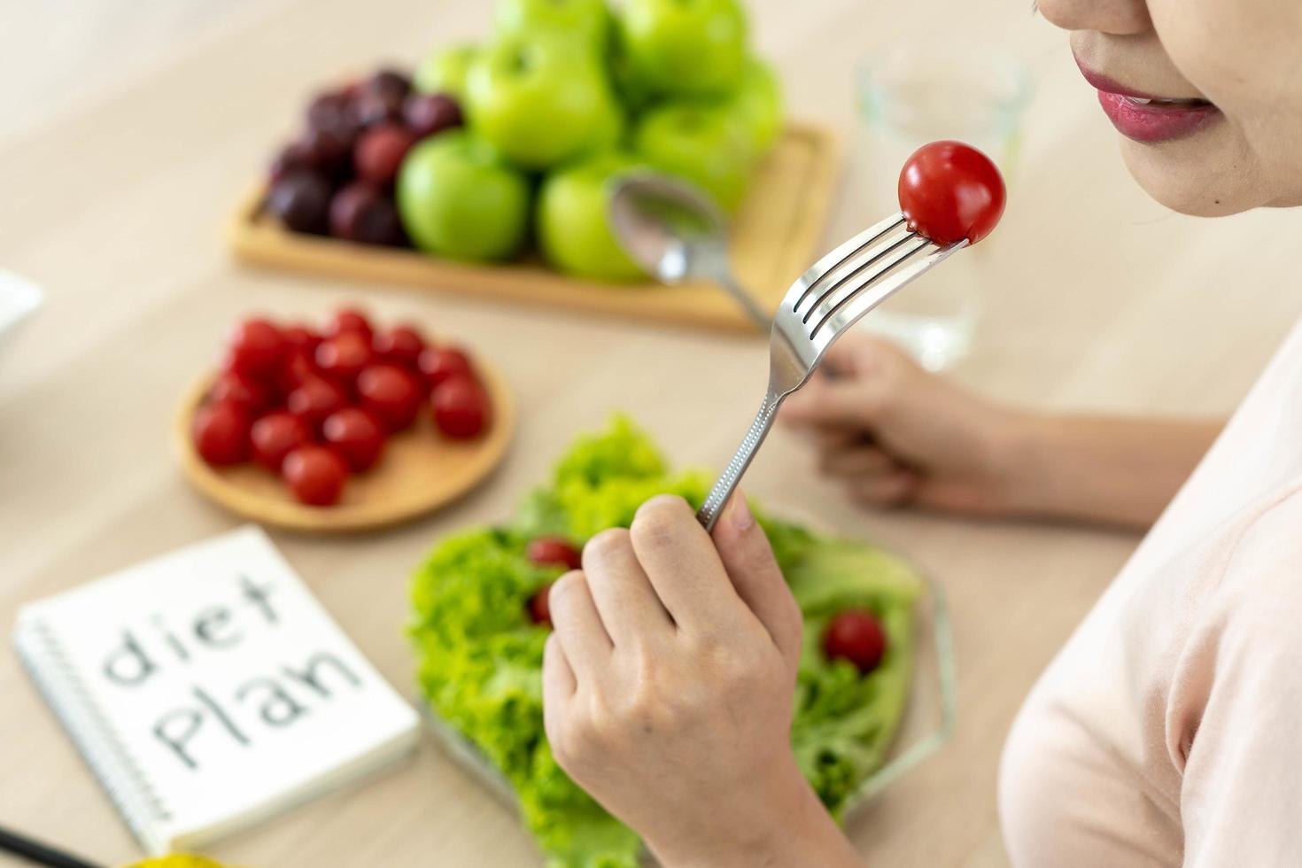 comida sana. las mujeres planean hacer dieta para una forma delgada y saludable. mujer comiendo verduras, ensalada y tomates foto