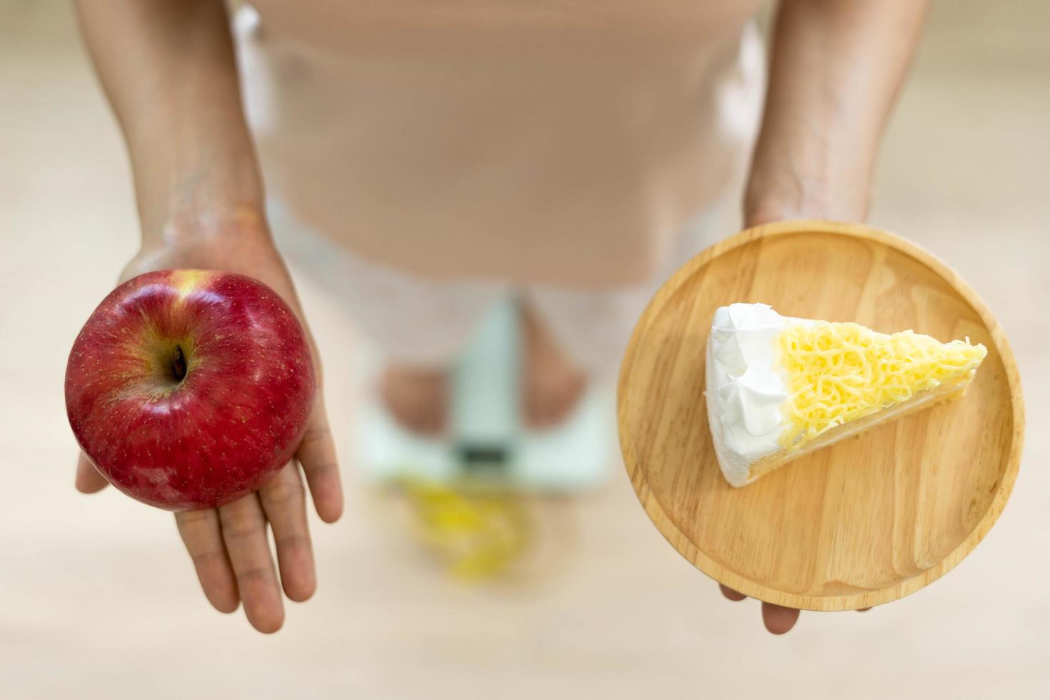 Women are choosing the right food for good health. Women are fasting. Comparison options between donuts and  apples during weight measurement on digital scales. Diet concept. photo