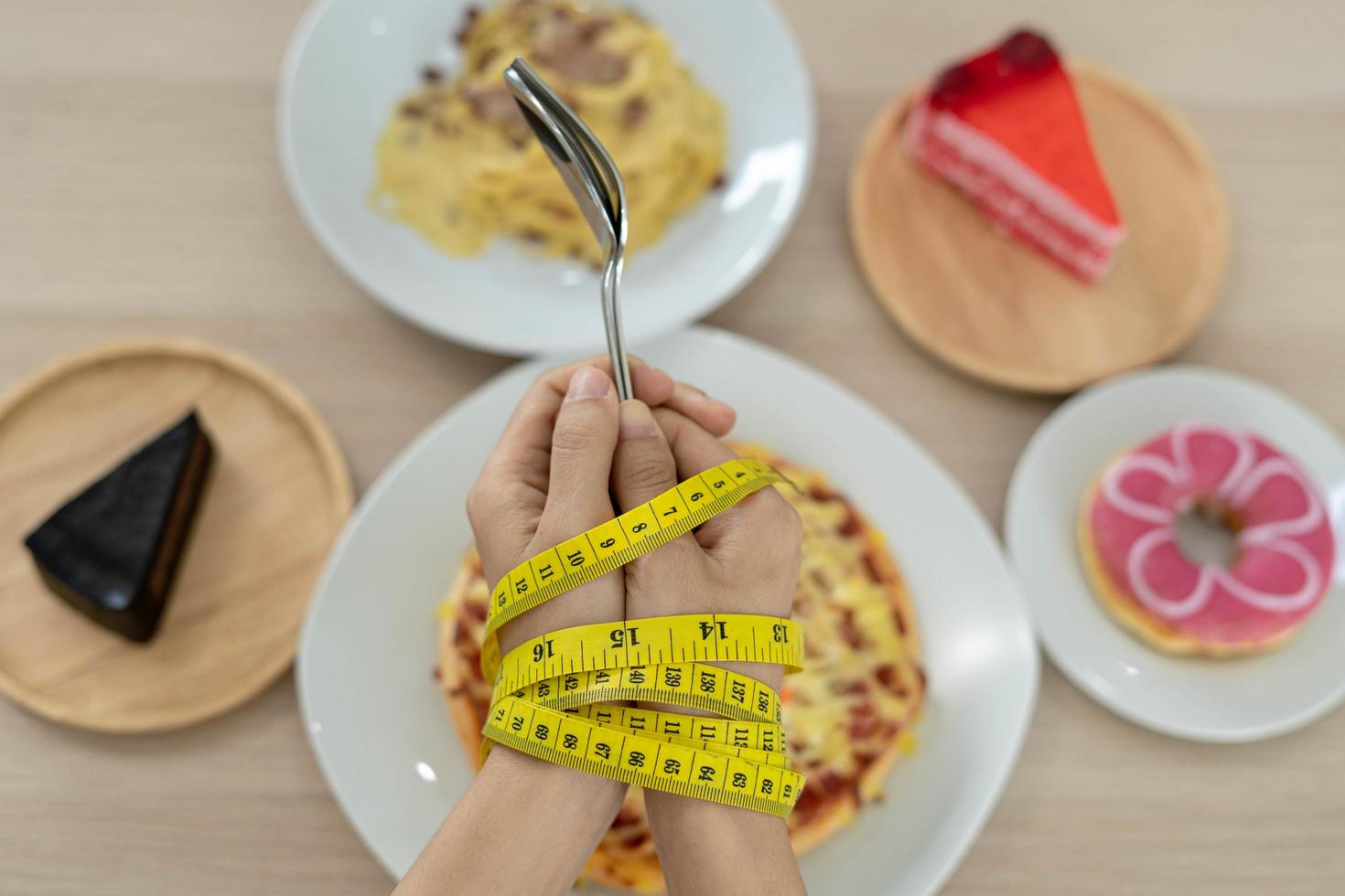 Tape measure around the arms of women. Stop eating trans fats, spaghetti, donuts, waffles and sweets. Lose weight for good health. Top view diet concept photo