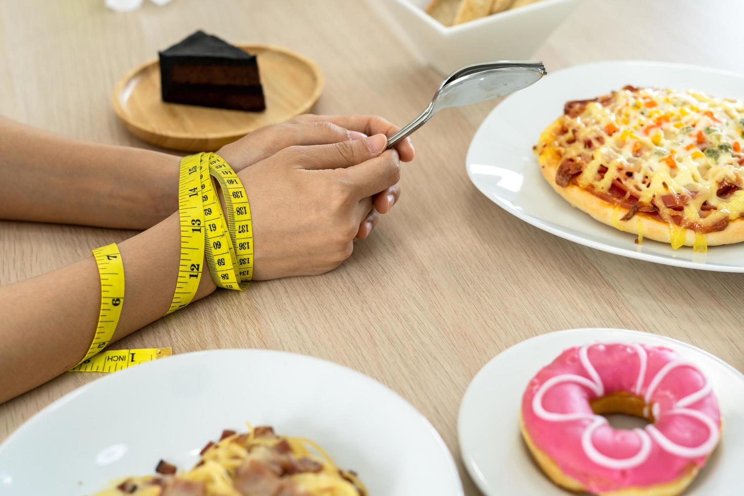 Tape measure around the arms of women. Stop eating trans fats, spaghetti, donuts, waffles and sweets. Lose weight for good health. Top view diet concept photo