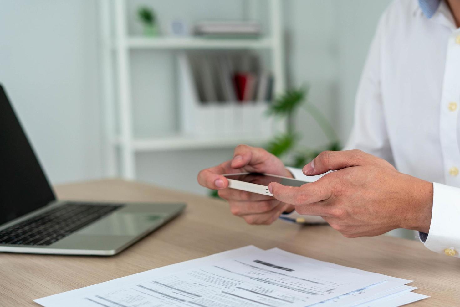 A business man uses his phone to scan a barcode to pay his monthly credit card bill after receiving an invoice. online bill payment concept photo