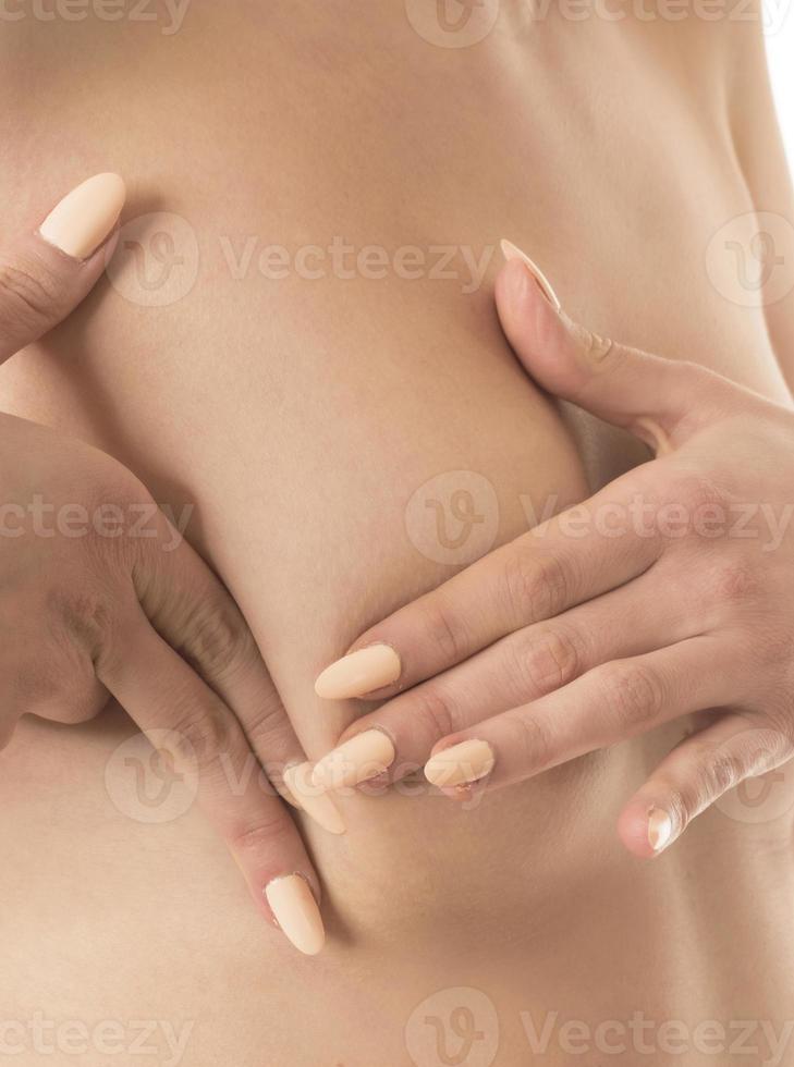 Woman hand checking lumps on her breast for signs of breast cancer photo