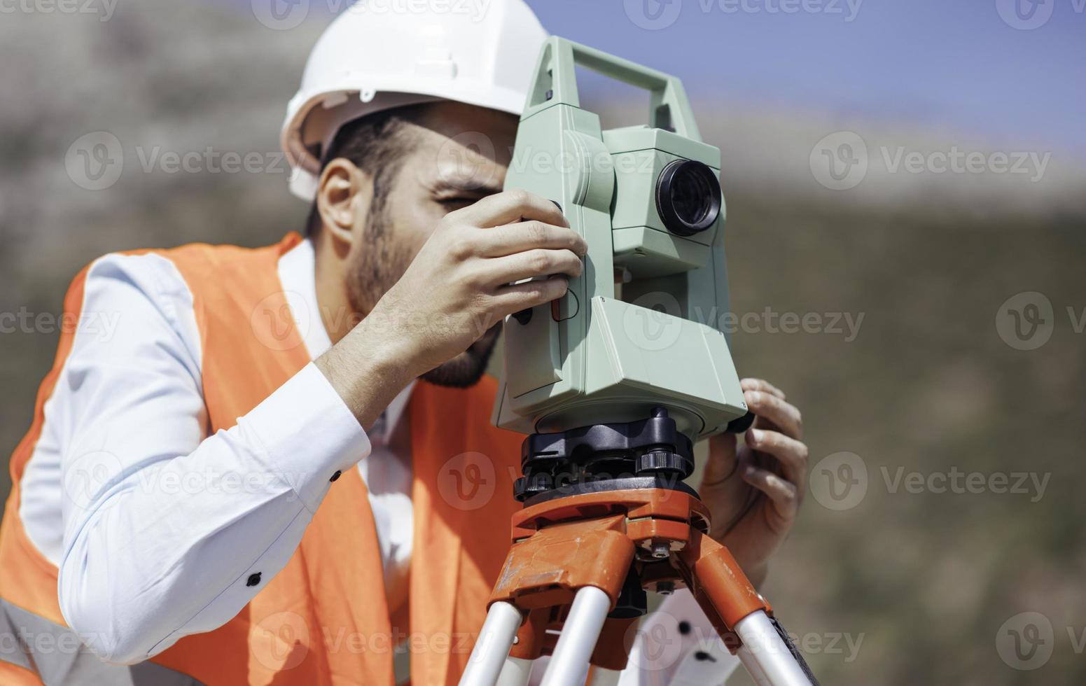 Surveyor engineer worker making measuring with theodolite equipment at construction site during road works photo