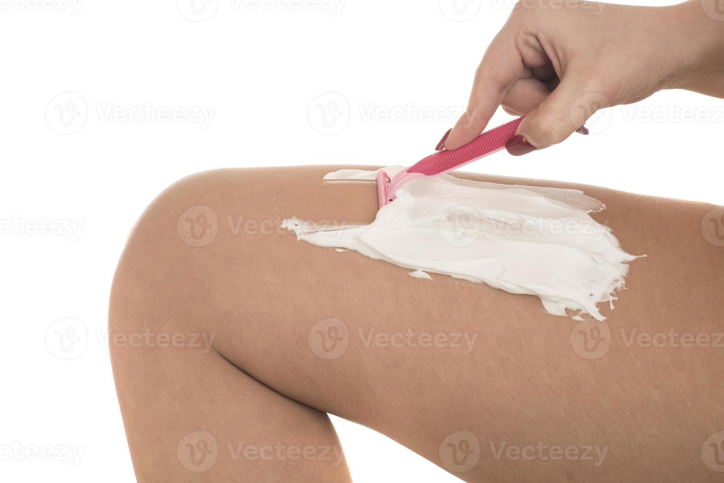young woman shaving her legs with razor photo