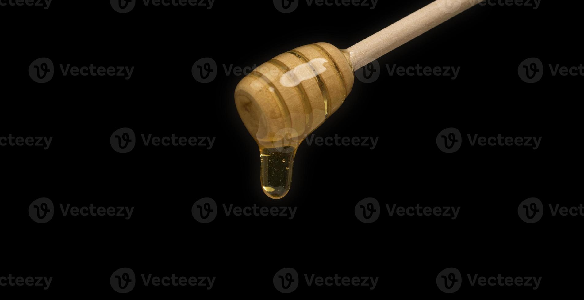 dripping honey on wooden dipper white background with room for copy space photo