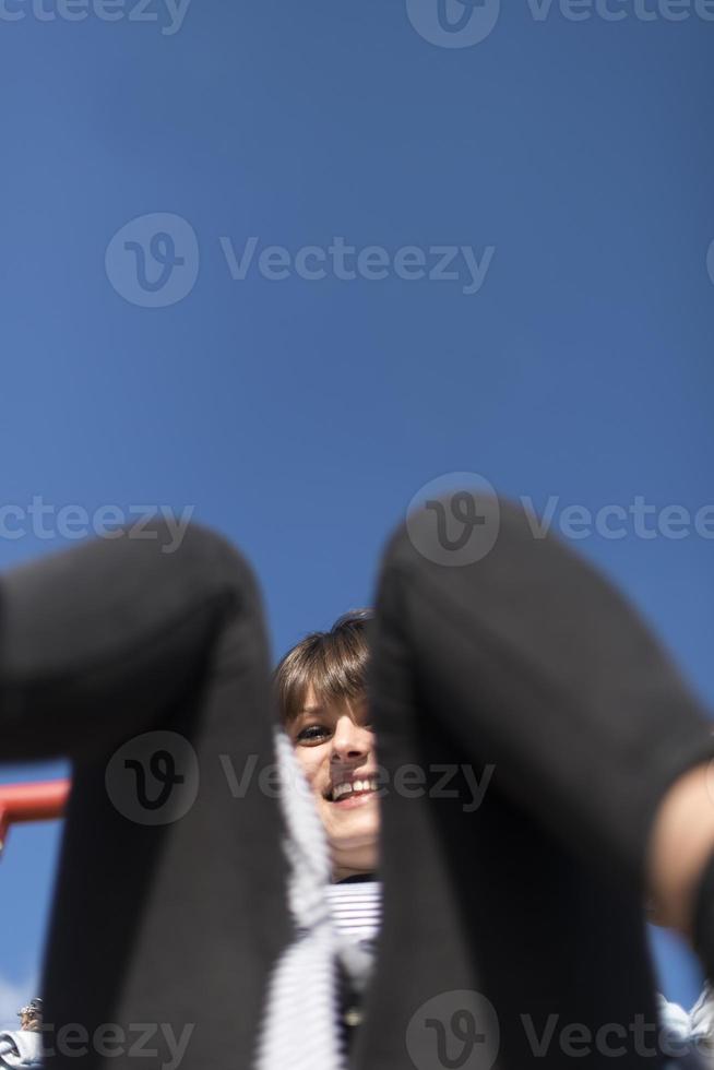 An infantile and happy woman sitting on a kid slide on a playground photo