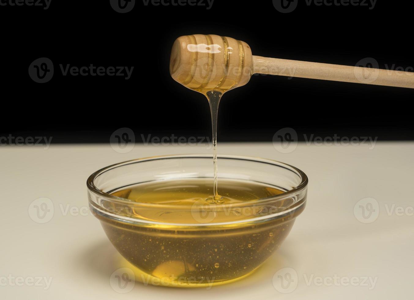 dripping honey on wooden dipper white background with room for copy space photo