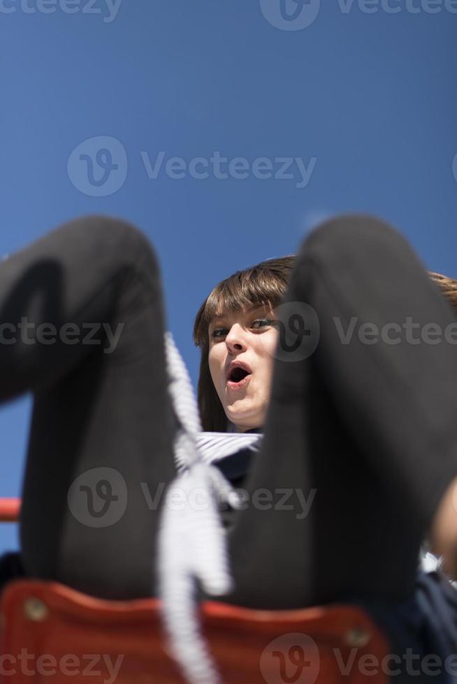 An infantile and happy woman sitting on a kid slide on a playground photo