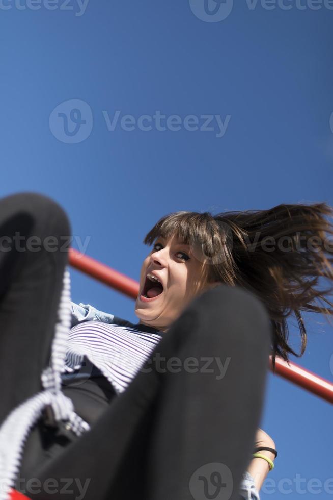 una mujer infantil y feliz sentada en un tobogán para niños en un patio de recreo foto