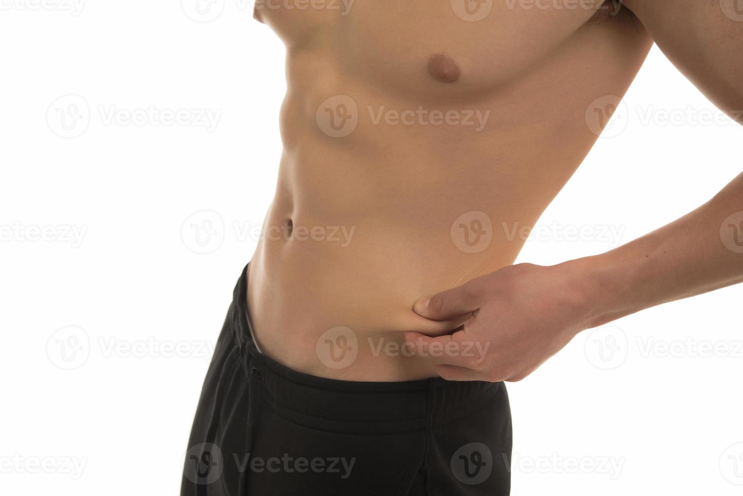A fit young man pinching body fat on his stomach photo