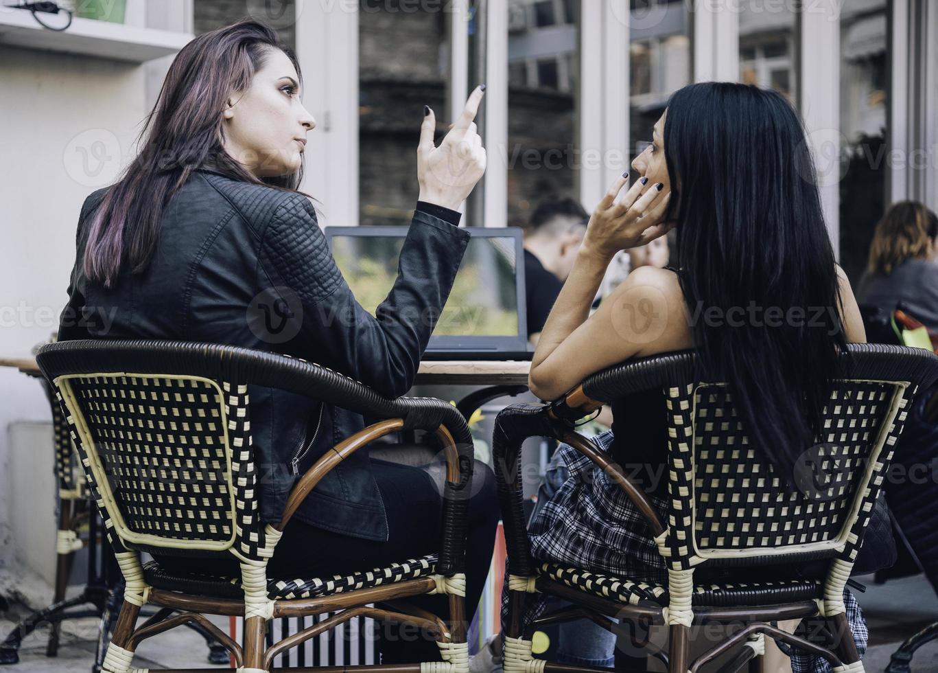 dos novias felices mirando el escaparate mientras están de pie con bolsas de compras cerca del centro comercial foto