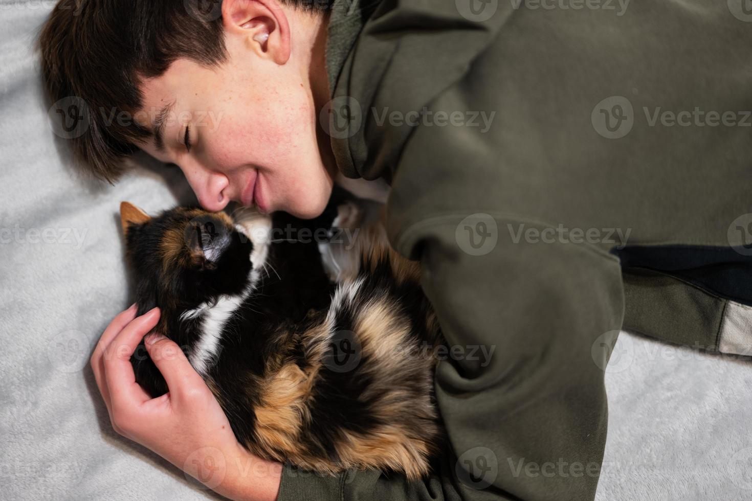 Teenager boy with kitty lying on the sofa. Children's love for pets. photo