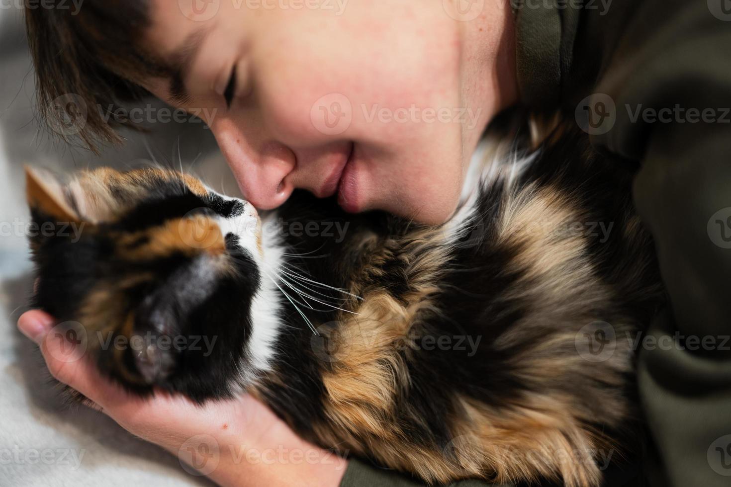 Teenager boy with kitty lying on the sofa. Children's love for pets. photo