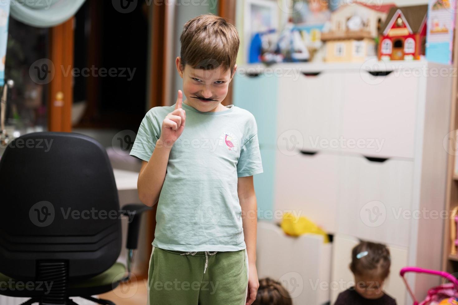 Boy wore a toy mustache in the children's room. photo
