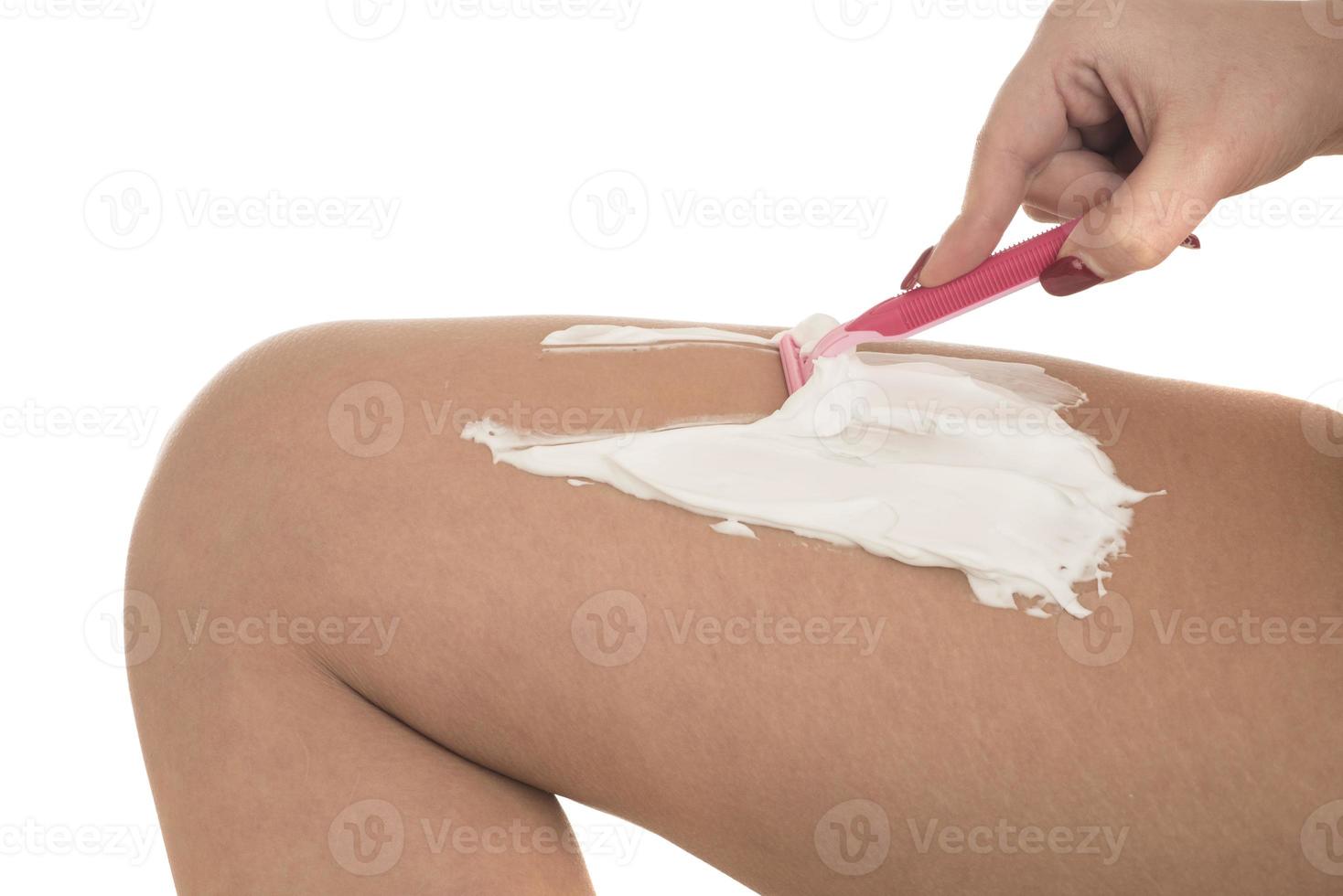 young woman shaving her legs with razor photo