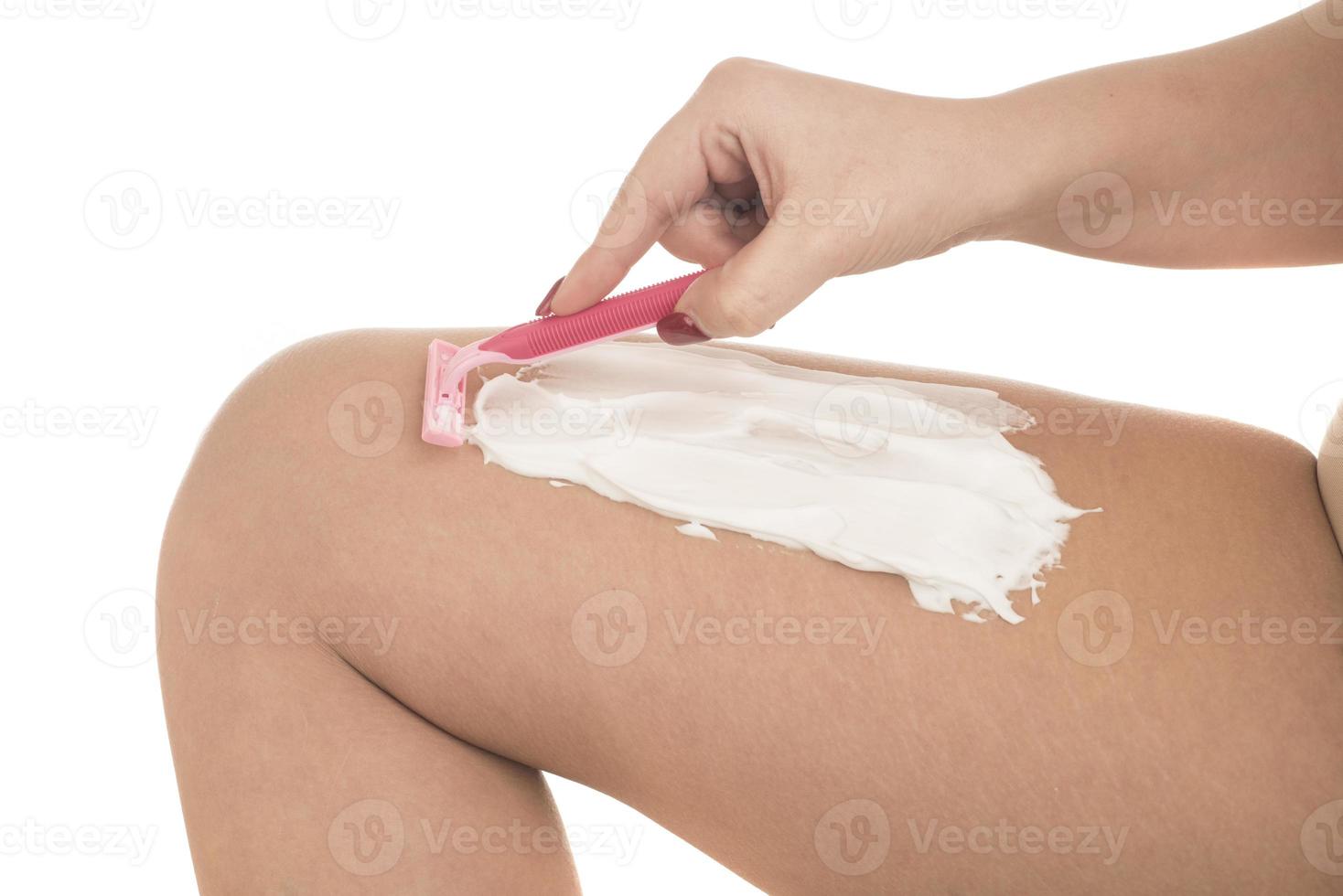 young woman shaving her legs with razor photo