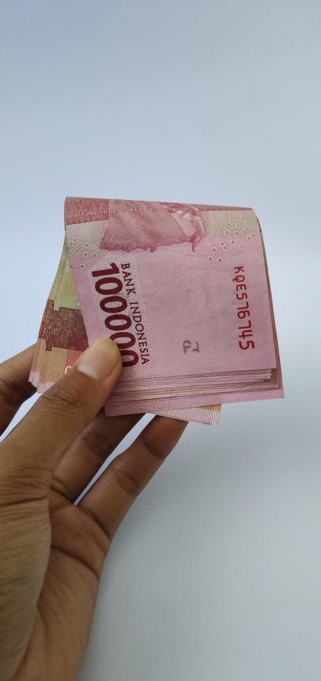 retrato de billetes de banco indonesios rp. 100.000 en mano. moneda rupia indonesia aislado sobre fondo blanco foto