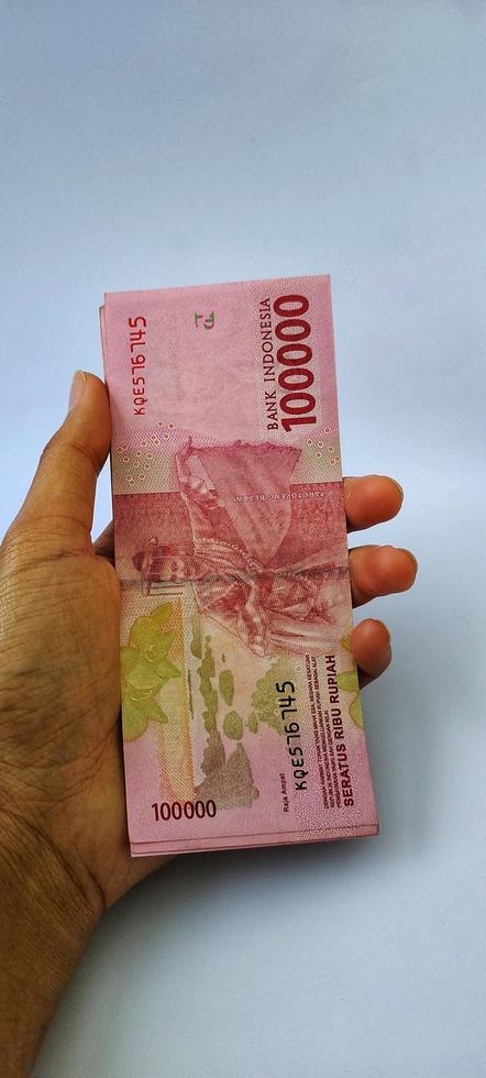 retrato de billetes de banco indonesios rp. 100.000 en mano. moneda rupia indonesia aislado sobre fondo blanco foto