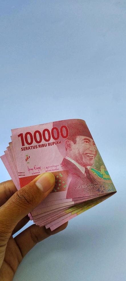 Portrait of Indonesian banknotes Rp. 100,000 in hand. Indonesian rupiah currency isolated on white background photo