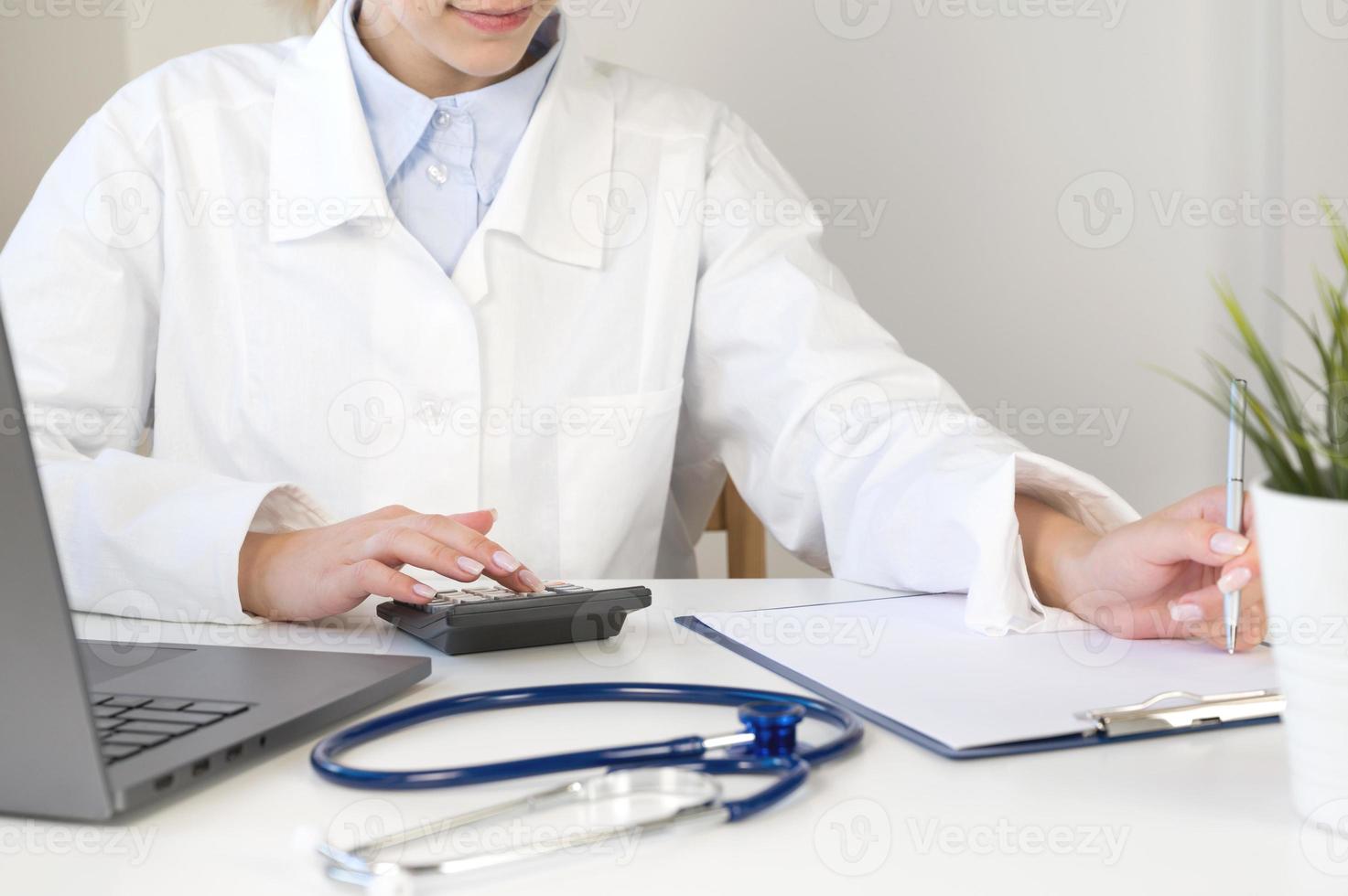 Healthcare costs and fees concept.Hand of smart doctor used a calculator and tablet photo