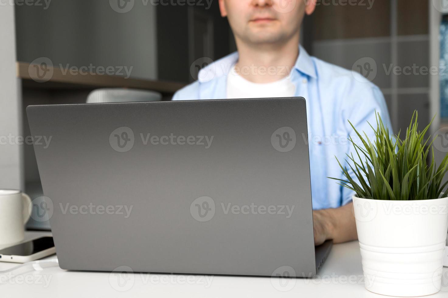 Young asian male working on laptop wearing.Remote work or education.Selective focus on laptop photo