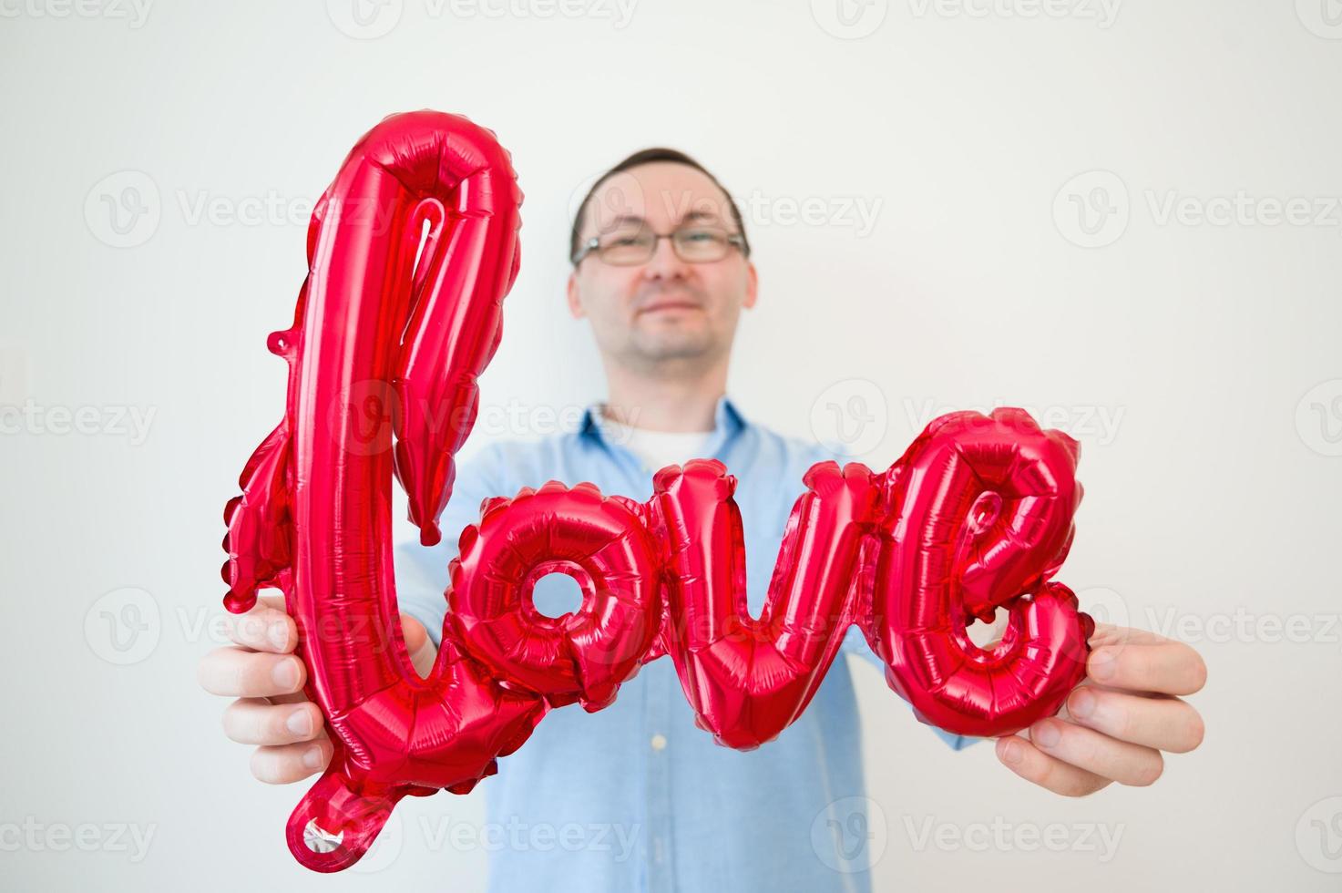 concepto de día de san valentín con hombre feliz con globo de amor. enfoque selectivo en globo. foto