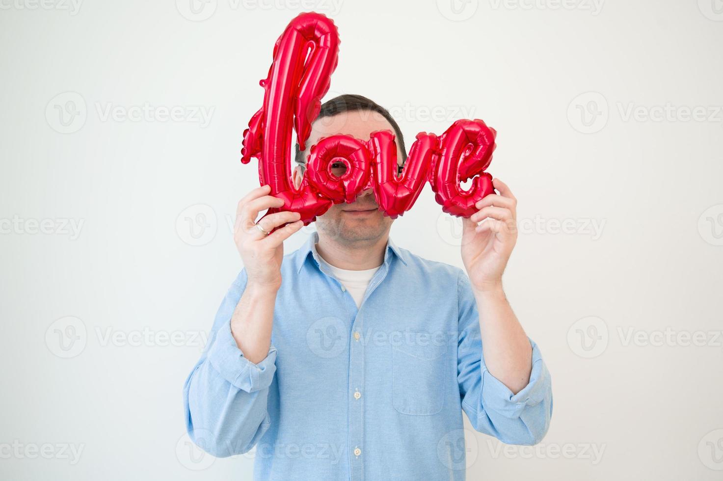 Valentines day concept. Portraint of happy man looking thriugh balloon photo