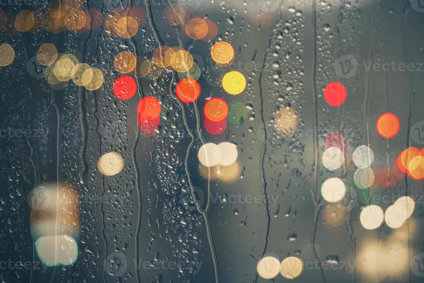 gotas de lluvia en la ventana y el fondo de las luces de la calle por la noche foto