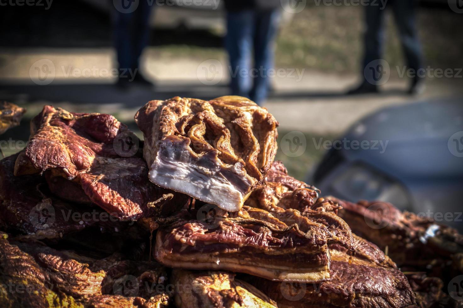 An outdoor stall with pieces of bacon and dried meat being sold photo