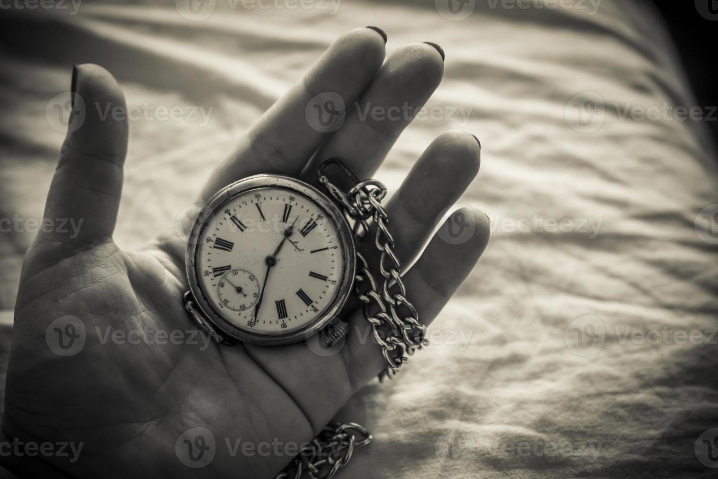un primer plano de la mano de una mujer sosteniendo un reloj retro en blanco y negro foto