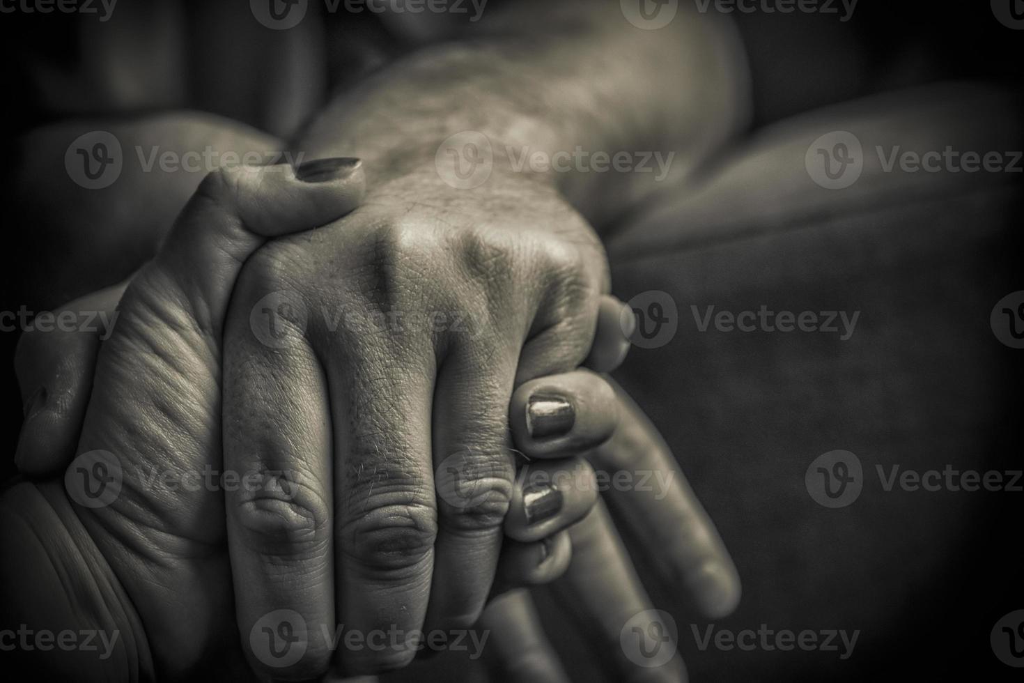 A close-up of man and woman holding hands in black and white photo