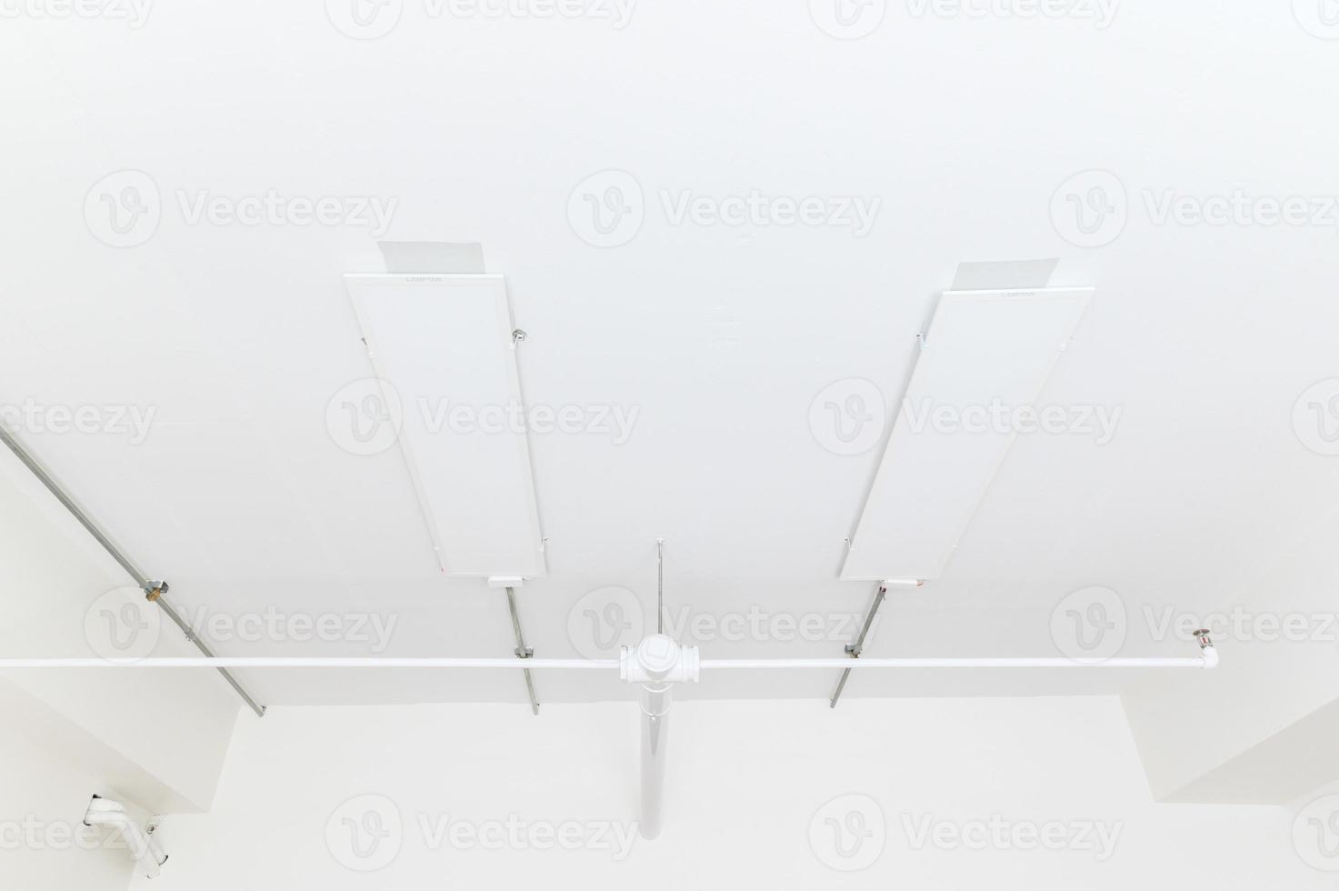 Electrical wires and pipes on house concrete ceiling background, plastic hoses with cables in empty room. Lines of pvc tubes, conduit after professional work. Renovation of home or factory interior photo
