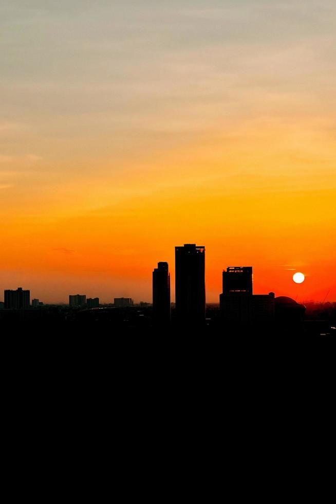 la silueta de la puesta de sol sobre el horizonte de la ciudad de bangkok. imagen vertical foto