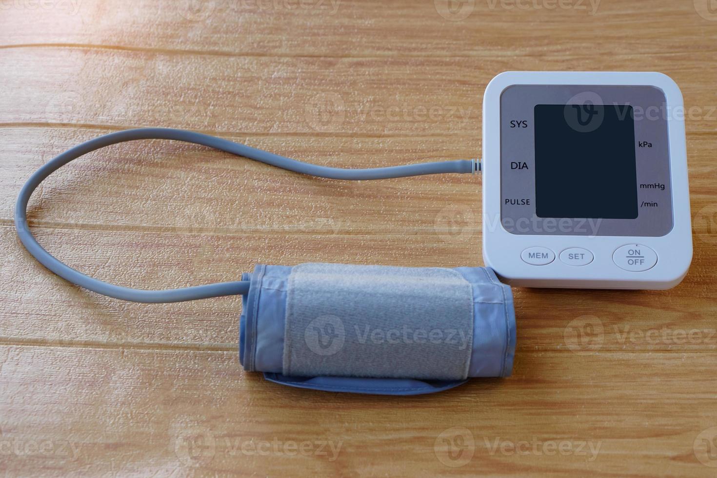 Digital blood pressure equipment with blank screen  on brown wooden floor. Blank screen of monitor for text. Concept, health care, hospital, clinic, doctor. Medical measurement tool for health check. photo