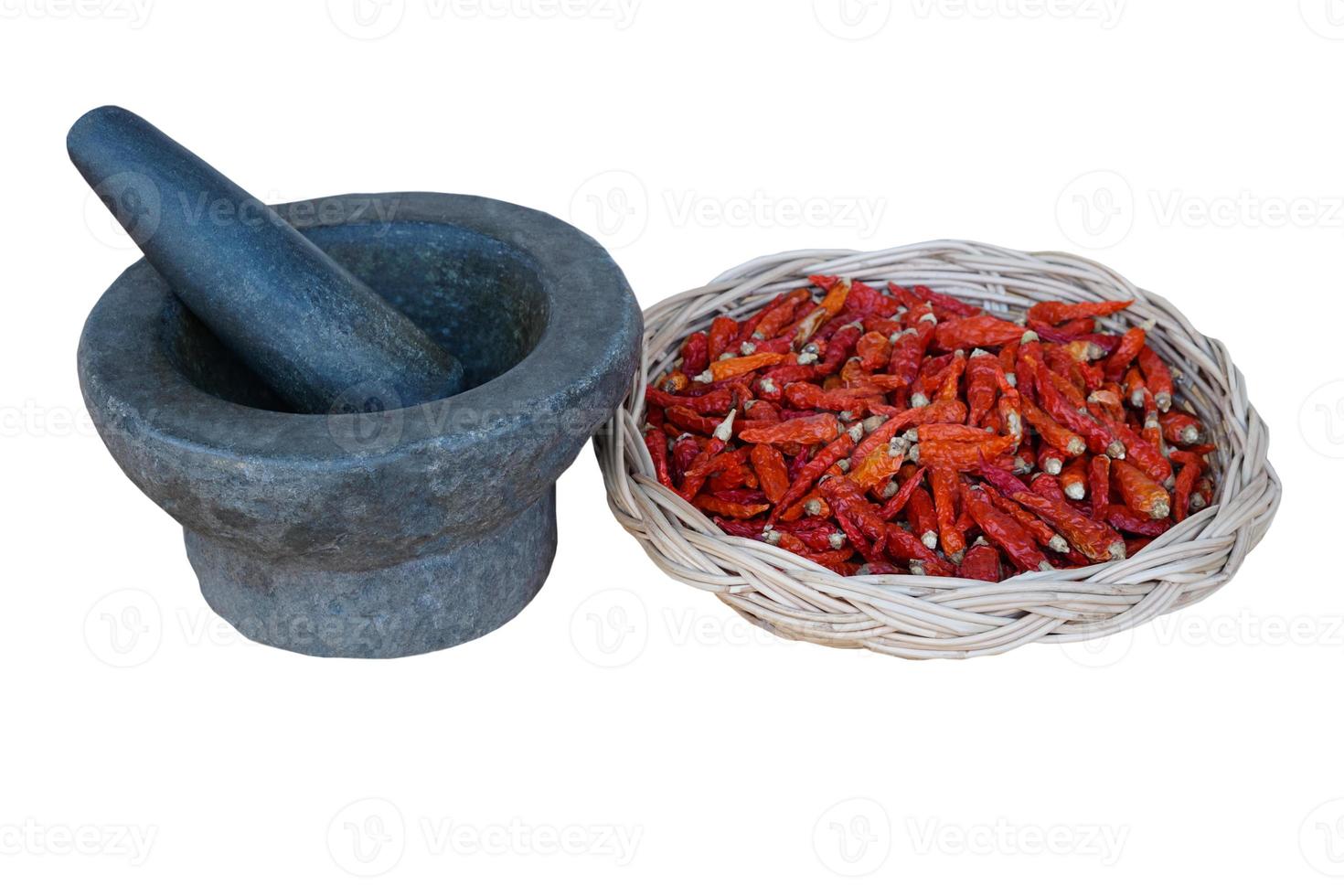 Old granite mortar with pestle and basket of red dried chillies for cooking on white background. Concept, kitchen utensils .Thai cooking tool, use to  pound chili paste or curry paste. photo
