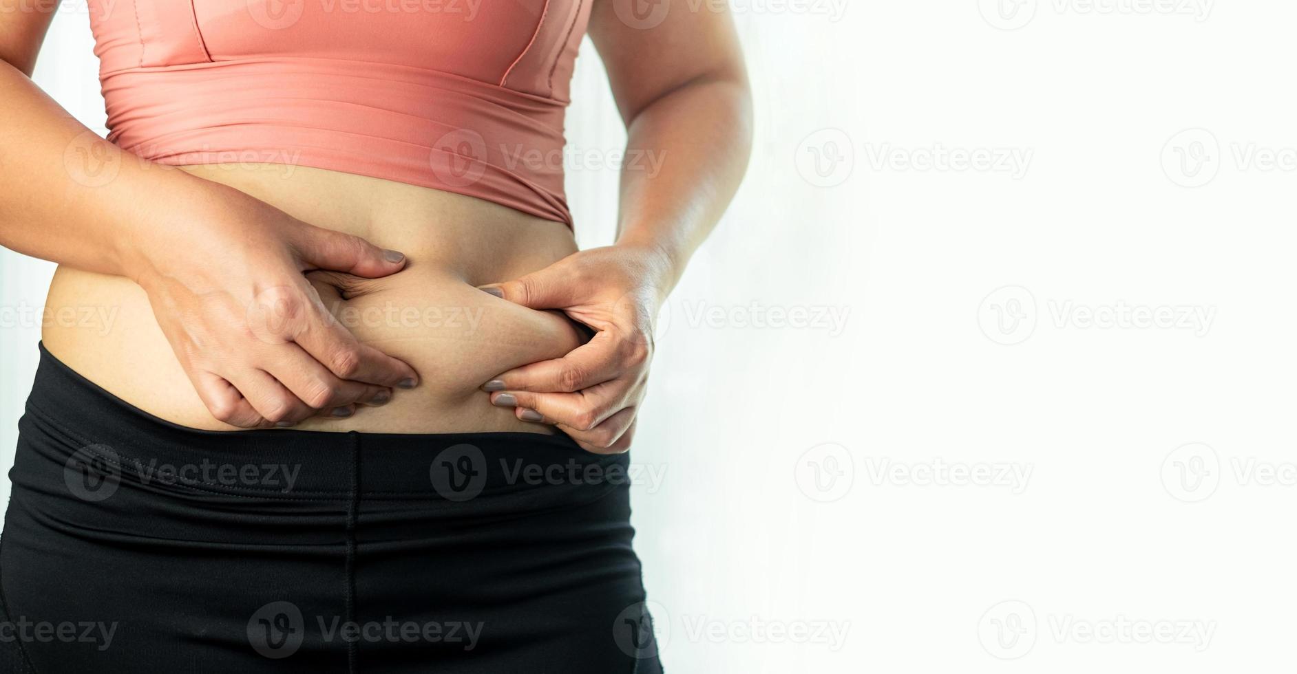 concepto de cuidado corporal, mano de mujer pellizcando su exceso de grasa abdominal, cuerpo de celulitis de mujer gorda y malsana aislado en fondo blanco foto