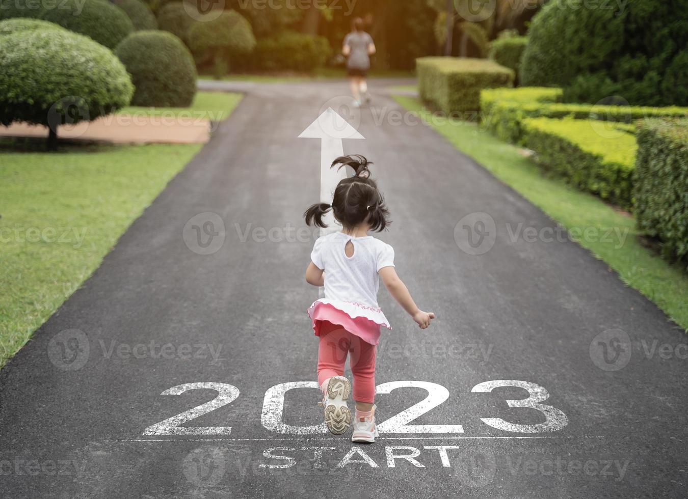 Asian baby running start into the new year 2023. Start up of runner woman running on nature race track go to Goal of Success. People running as part of Number 2023. Sport health care. photo