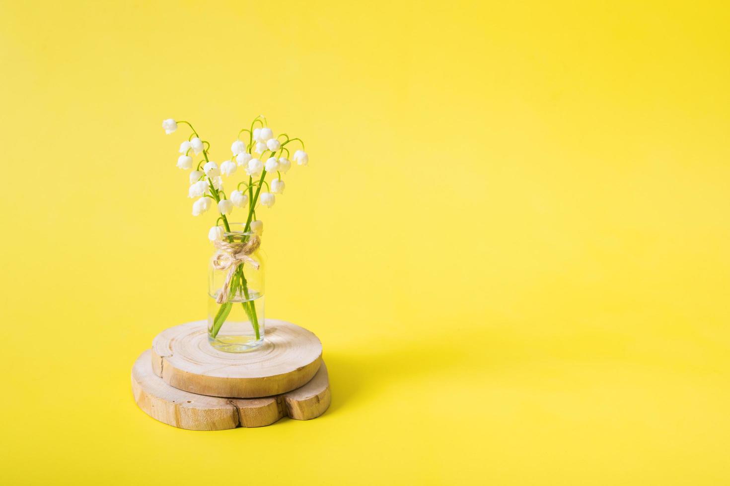 Lilies of the valley bouquet in a miniature jar on a yellow background with copy space. Mothers day blank greeting card photo