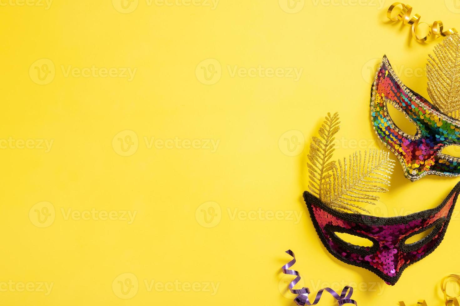 Festive face mask for carnival celebration on yellow background. Copy space. Carnival flat lay photo