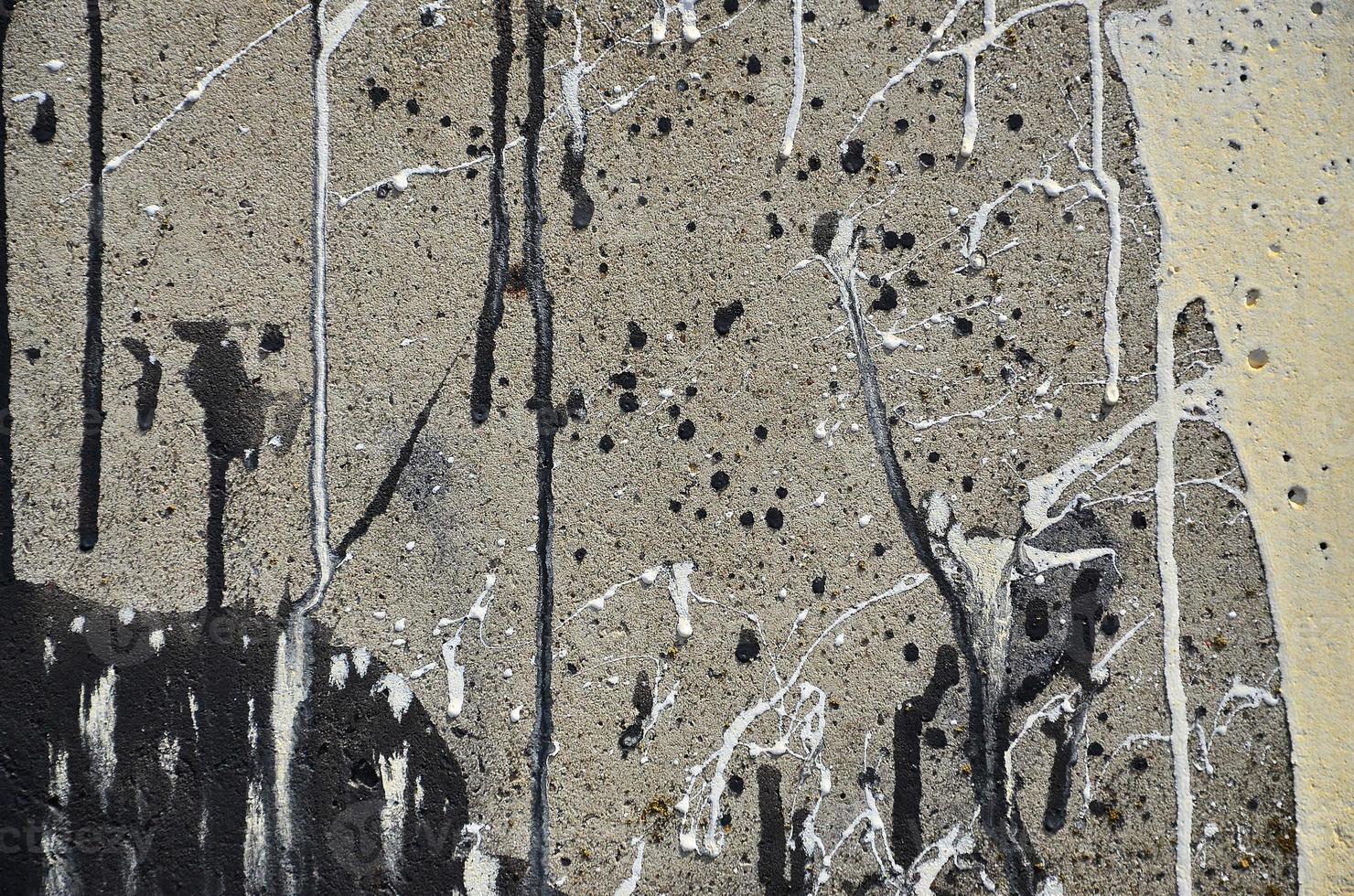 A photograph of a close-up of black paint spots on a concrete wall. Pouring paint on the wall in random order. The concept of graffiti and street art culture photo